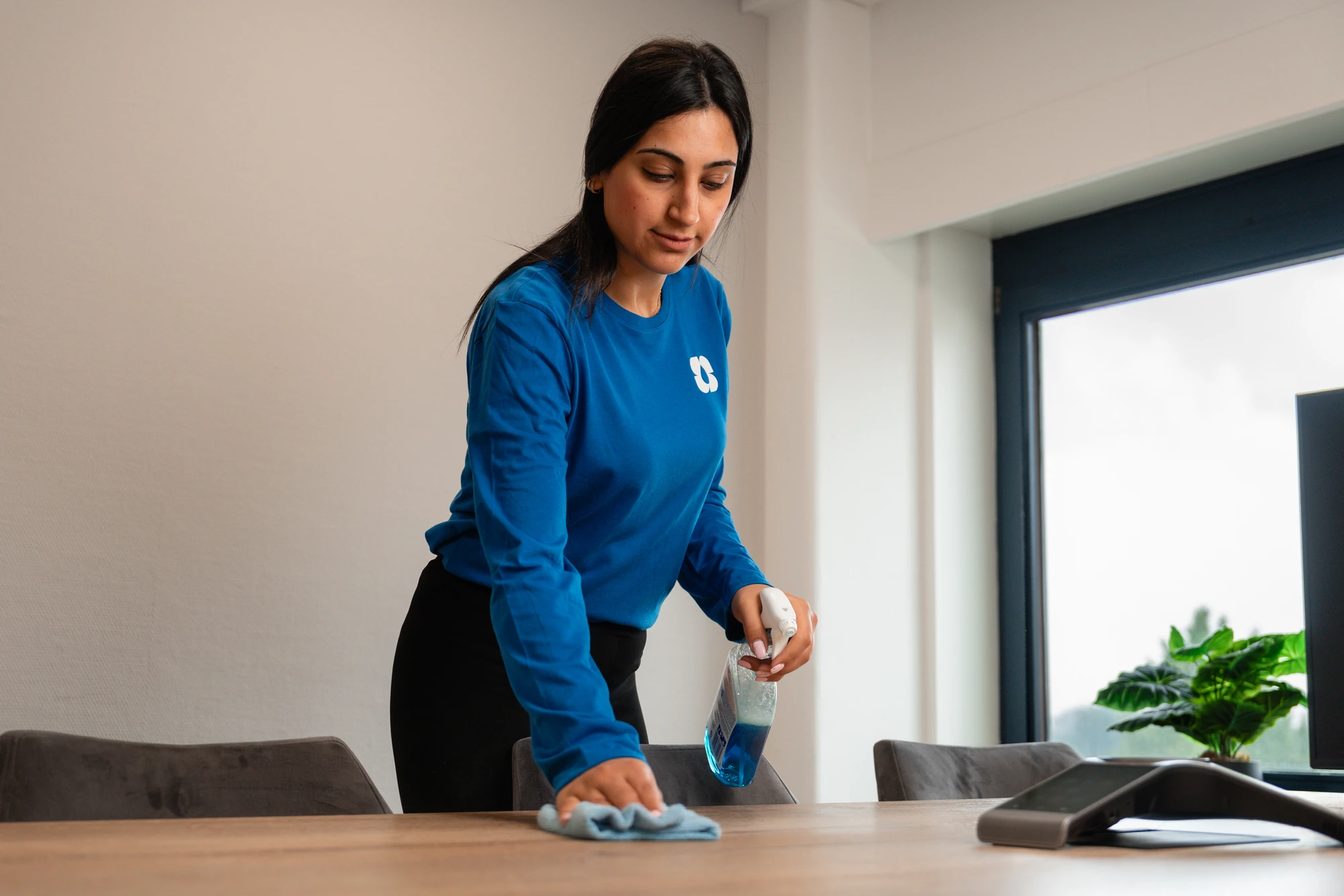 Schoonmaakster maakt een tafel schoon in een kantoor