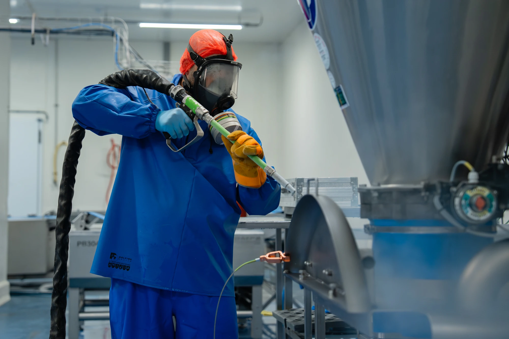 Medewerker met gehoorbescherming reinigt een productiemachine