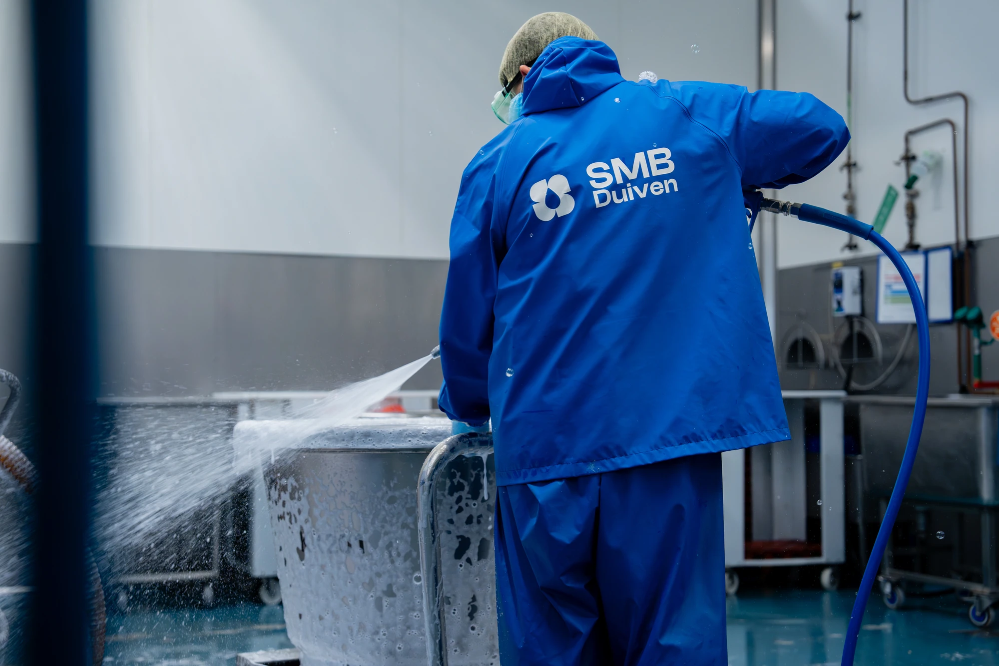 Medewerker reinigt een productieruimte met hogedruk