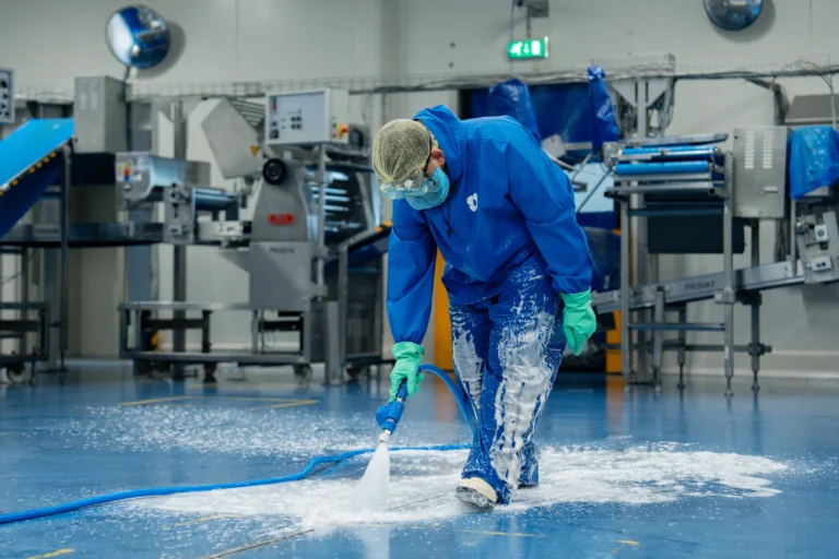 Medewerker reinigt de vloer van een productieruimte