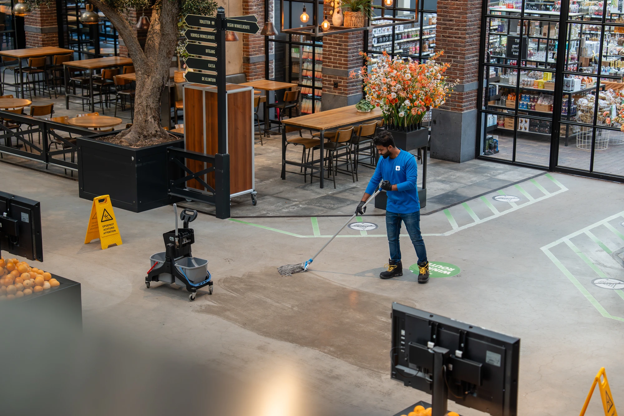 Medewerker van SMB Duiven maakt schoon in een winkelruimte