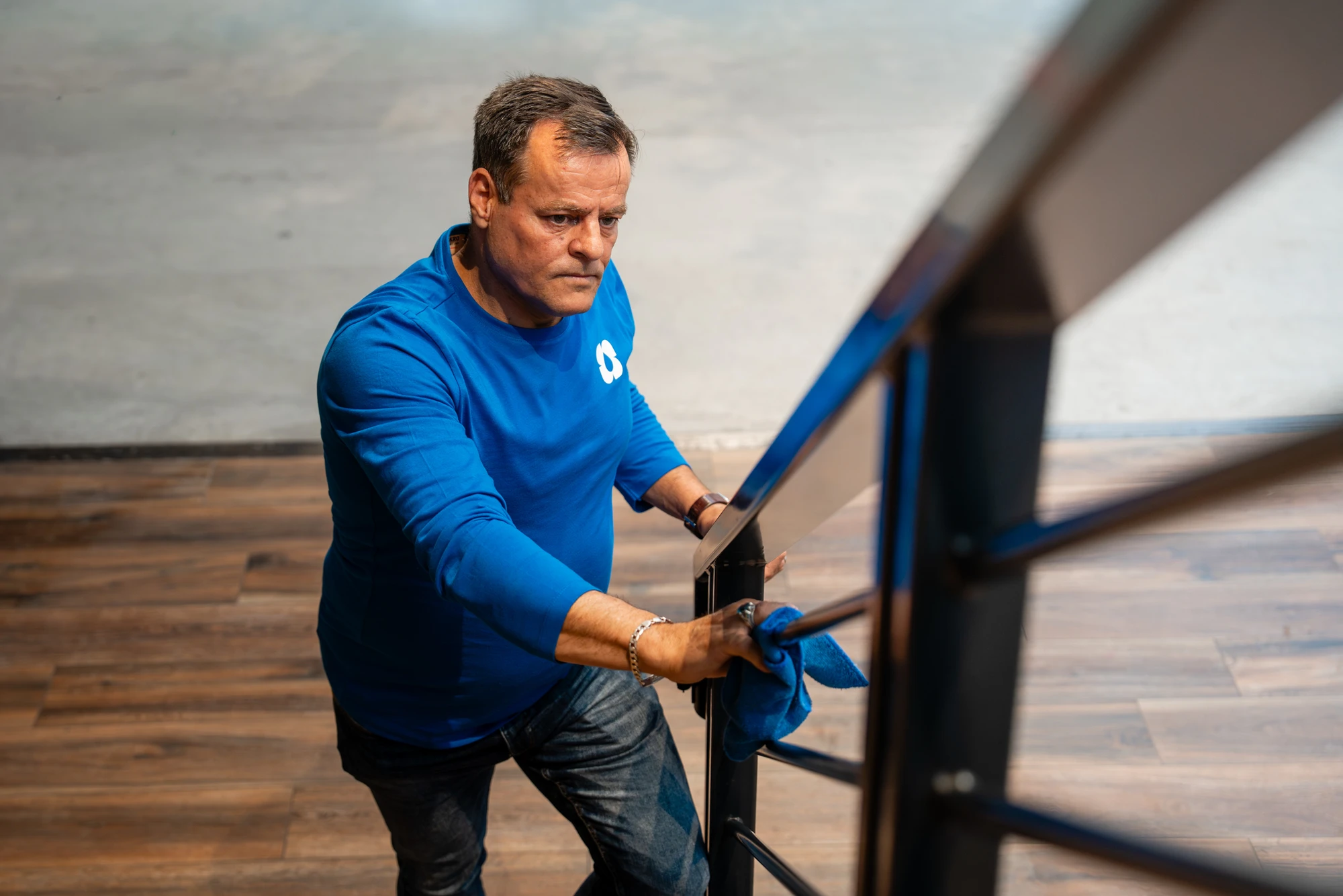 Medewerker van SMB Duiven reinigt een trapleuning