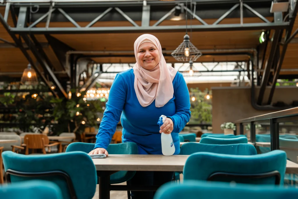 Medewerker van SMB Duiven reinigt tafels in een kantine