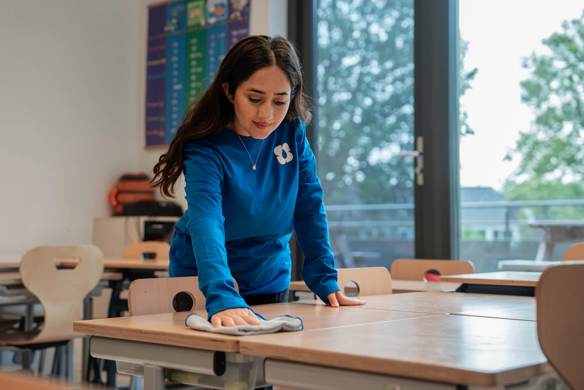 Schoonmaakster reinigt een tafel in een klaslokaal