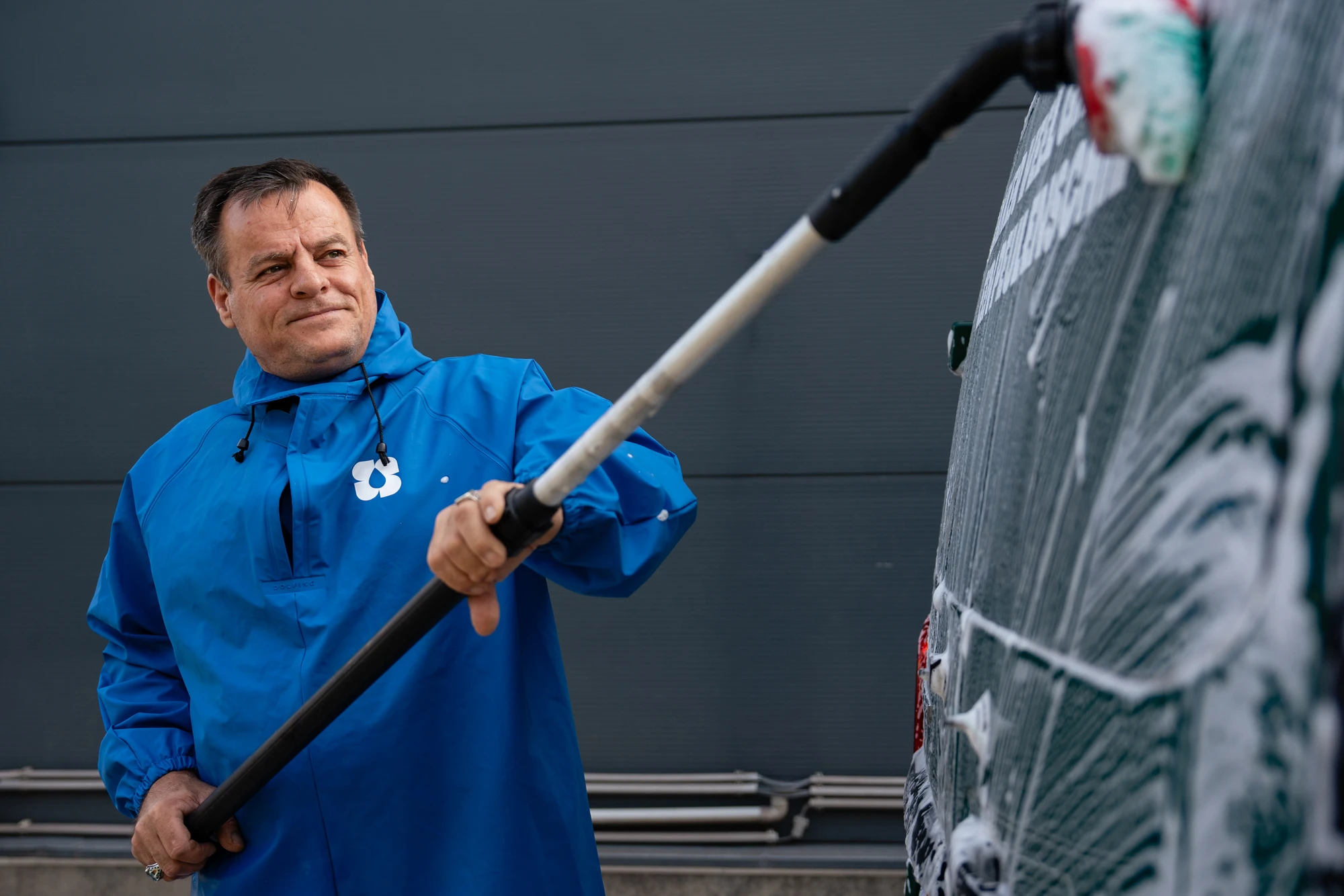 Medewerker reinigt een bedrijfswagen met een hogedrukspuit