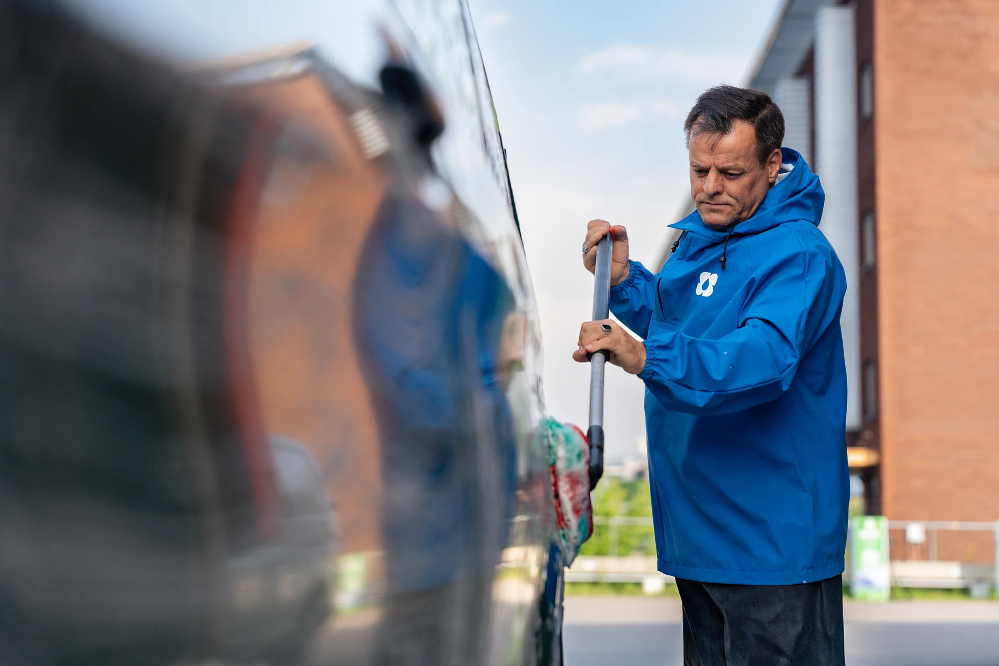 Medewerker van SMB Duiven reinigt een bedrijfswagen met een hogedrukspuit