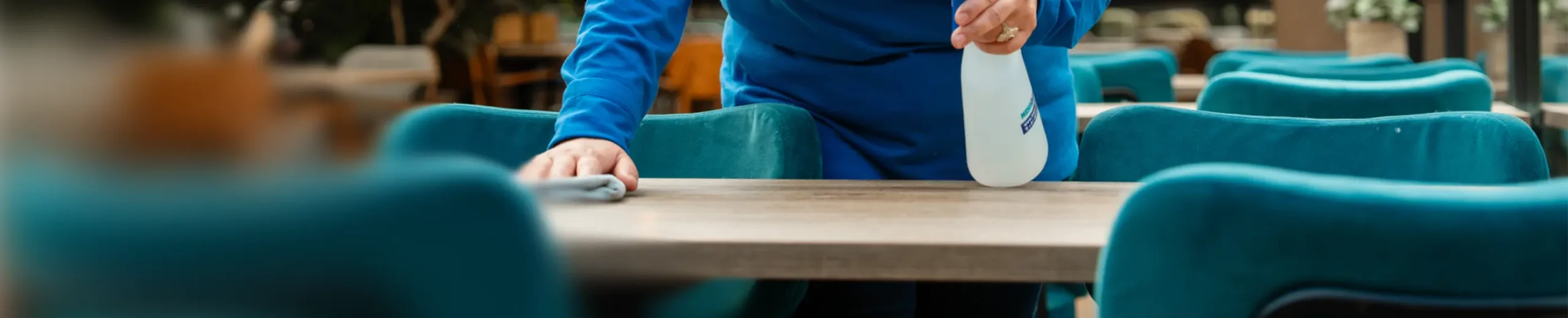 Medewerker van SMB Duiven maakt tafels schoon in een kantine