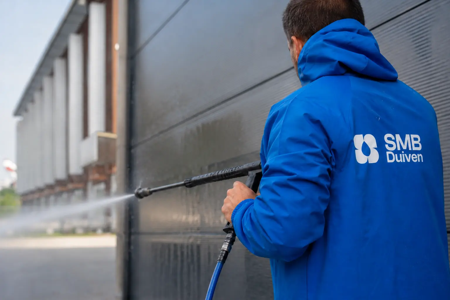 Medewerker van SMB Duiven reinigt glas aan de buitenkant van een pand